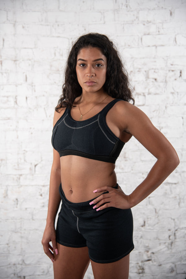 woman wearing Seraphina Safety Apparel flame-resistant boy short and safety bra standing with her hand on her hip against a white background. 