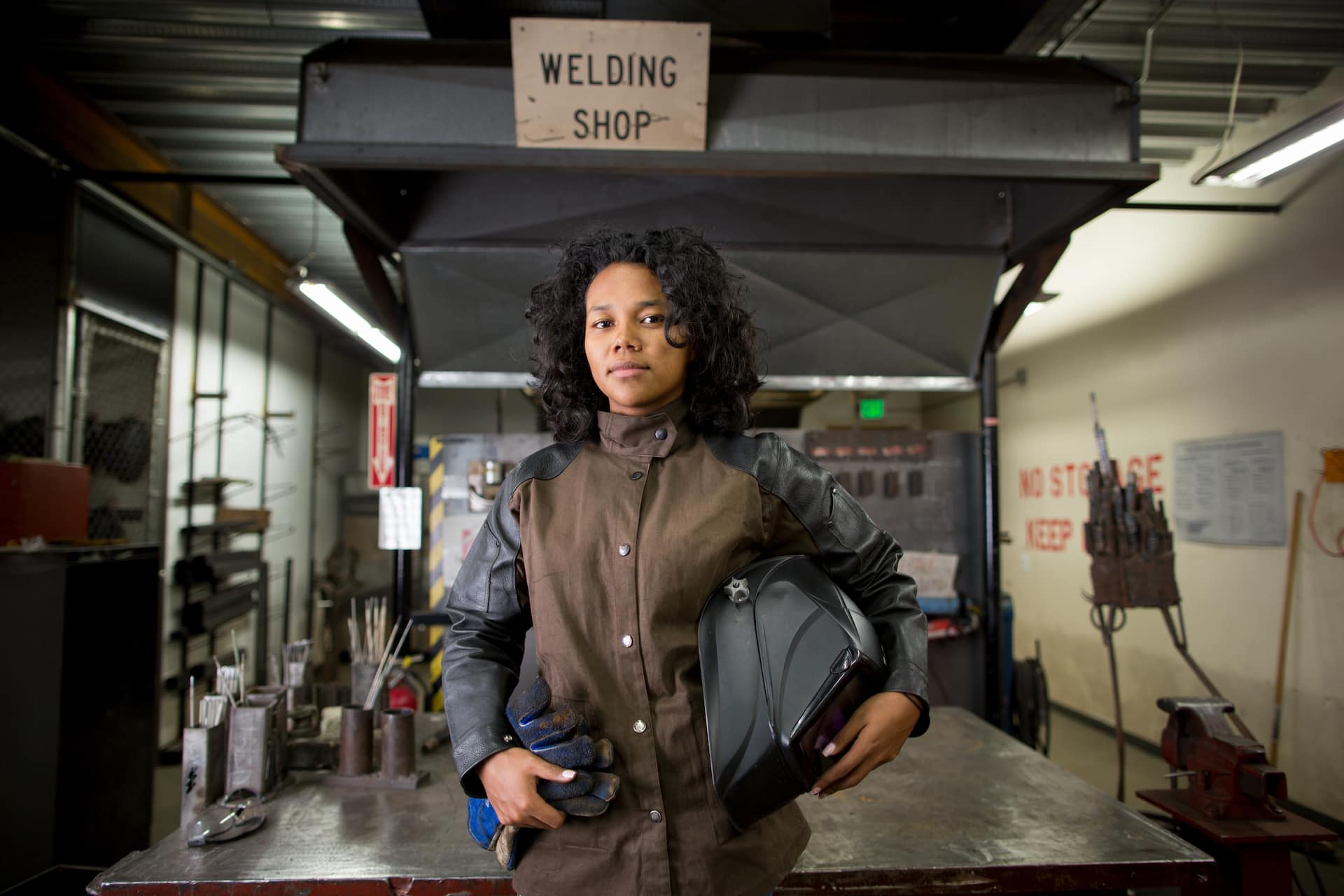Portrait of young female metalsmith in welding workshop